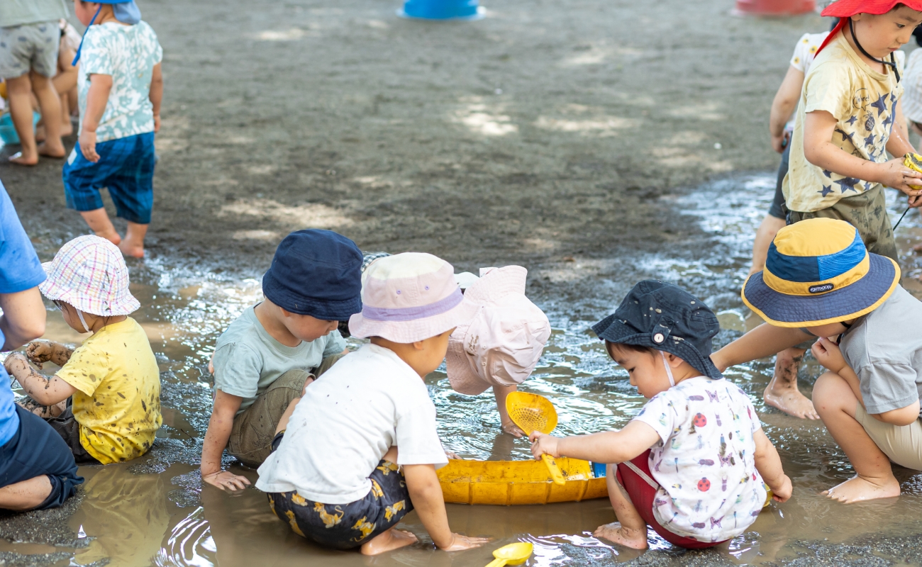 どろで遊ぶ子どもと先生