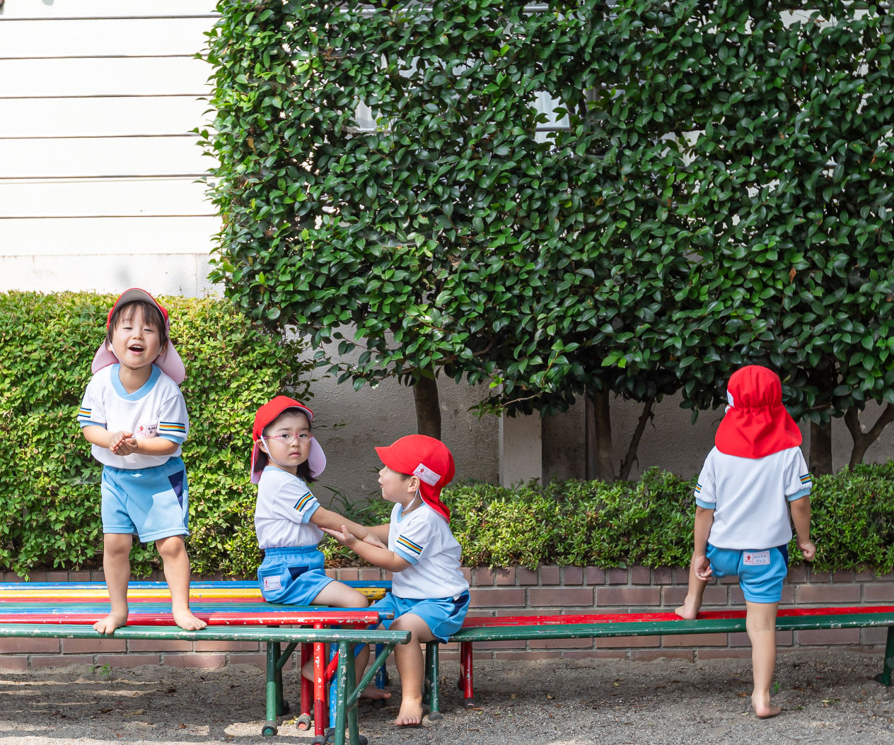 4人の子どもがベンチで遊ぶ様子
